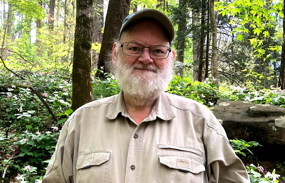 James Cheverud smiles in front of a forest